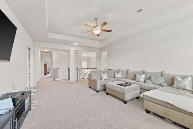 carpeted living room with ceiling fan and a raised ceiling