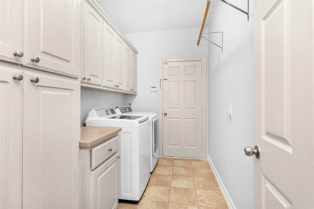 clothes washing area featuring washing machine and clothes dryer, light tile patterned floors, and cabinets