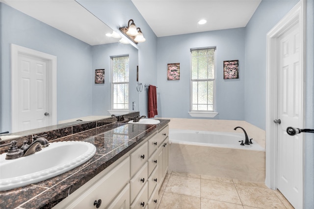 bathroom featuring tile patterned floors, plenty of natural light, vanity, and tiled tub