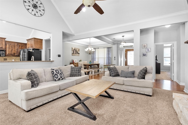 living room featuring vaulted ceiling, plenty of natural light, ceiling fan with notable chandelier, and light hardwood / wood-style flooring