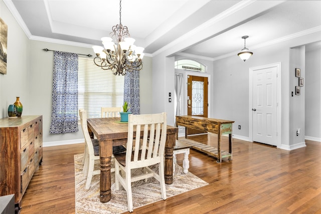 dining space featuring a raised ceiling, crown molding, wood-type flooring, and a notable chandelier