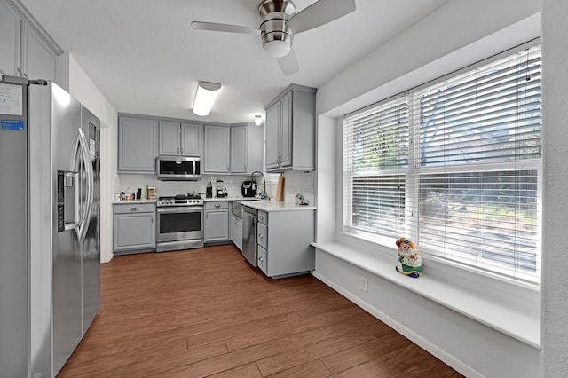 kitchen with dark wood-type flooring, appliances with stainless steel finishes, a wealth of natural light, and gray cabinets