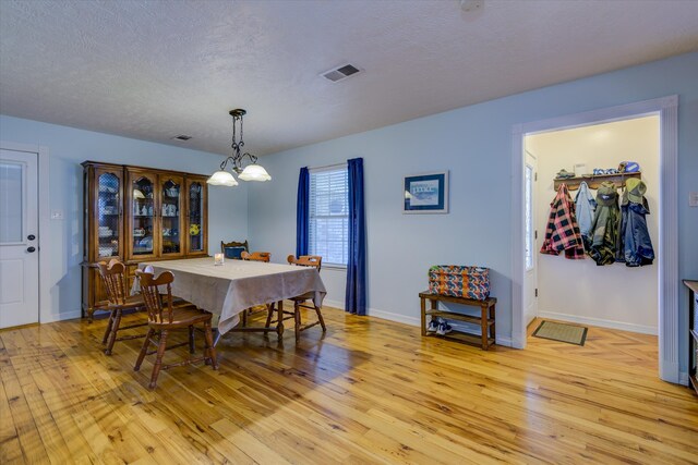 dining room featuring light hardwood / wood-style floors, an inviting chandelier, and a textured ceiling