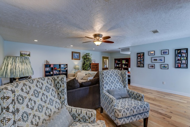 living room with a textured ceiling, light wood-type flooring, and ceiling fan