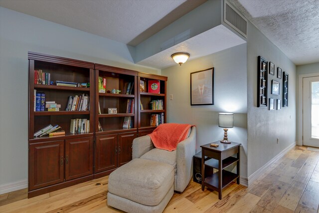 sitting room featuring a textured ceiling and light hardwood / wood-style flooring