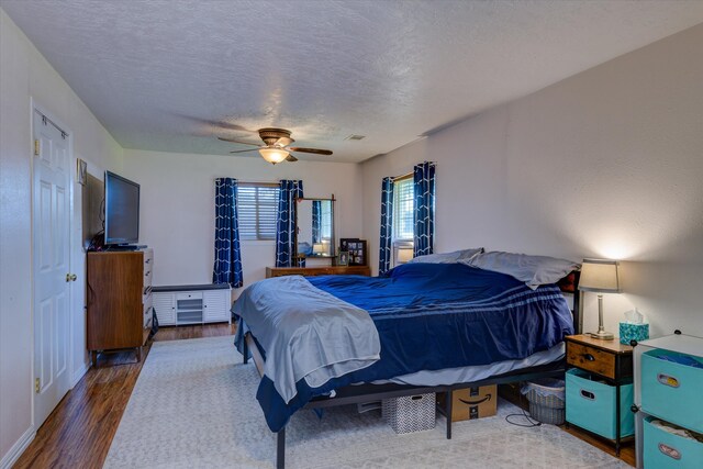 bedroom with ceiling fan, a textured ceiling, and dark hardwood / wood-style floors