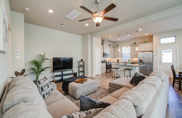 living room with light wood-type flooring and ceiling fan