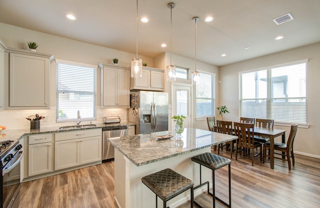 kitchen featuring decorative light fixtures, stainless steel appliances, sink, and a wealth of natural light