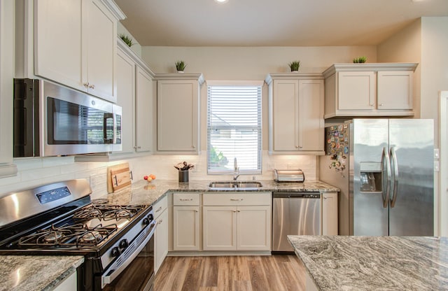 kitchen with light stone countertops, stainless steel appliances, and sink