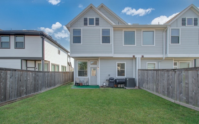 back of house with central air condition unit and a yard