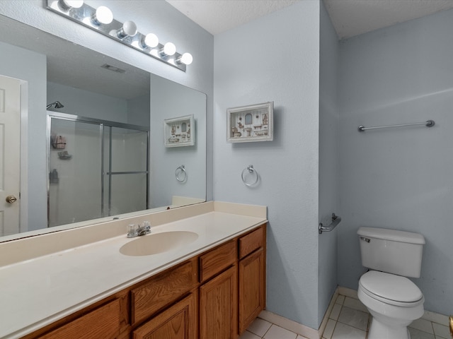 bathroom featuring toilet, vanity, tile patterned floors, and a shower with door