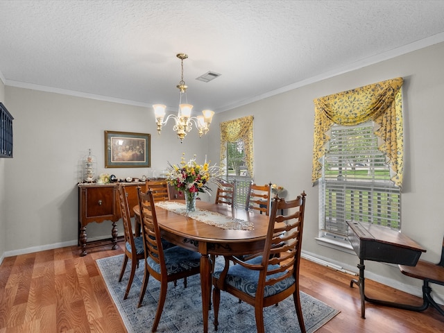 dining space featuring ornamental molding, a textured ceiling, hardwood / wood-style flooring, and a chandelier