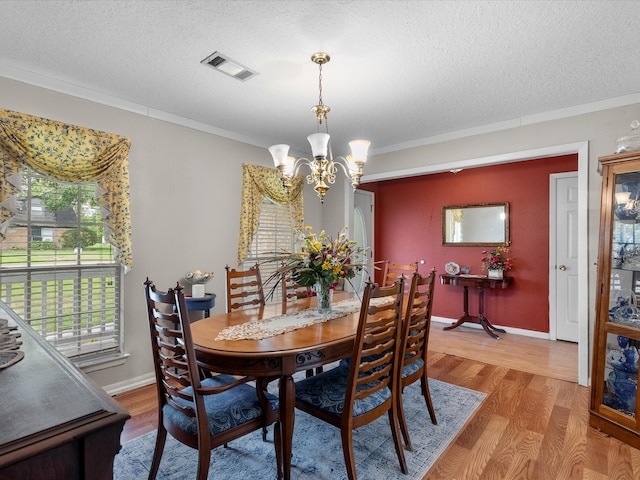 dining room with ornamental molding, hardwood / wood-style floors, a notable chandelier, and a textured ceiling