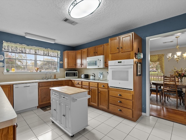 kitchen with a healthy amount of sunlight, sink, pendant lighting, and white appliances