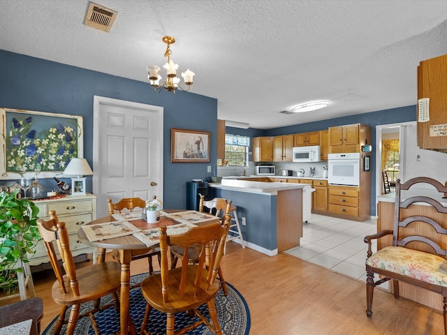 dining area featuring an inviting chandelier, a textured ceiling, sink, and light wood-type flooring