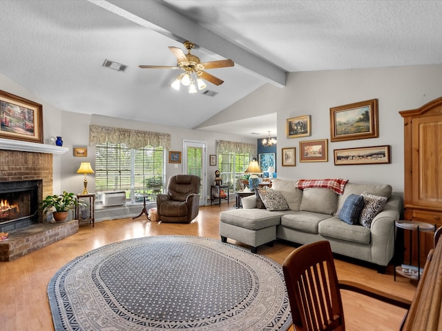 living room with vaulted ceiling with beams, a fireplace, light wood-type flooring, a textured ceiling, and ceiling fan with notable chandelier