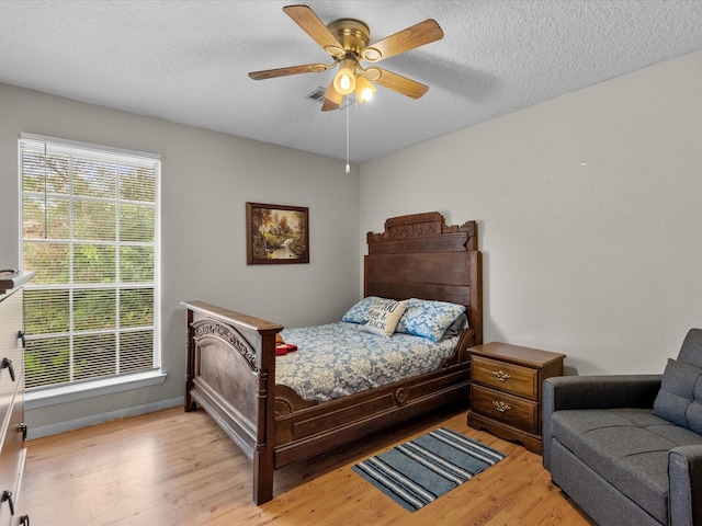 bedroom featuring a textured ceiling, light wood-type flooring, and ceiling fan