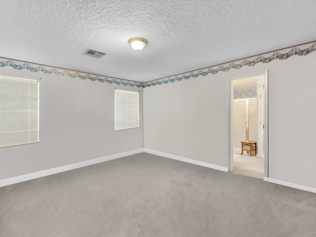 carpeted empty room featuring a textured ceiling