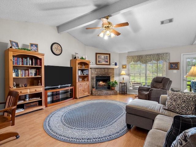 living room featuring hardwood / wood-style flooring, a brick fireplace, plenty of natural light, and lofted ceiling with beams