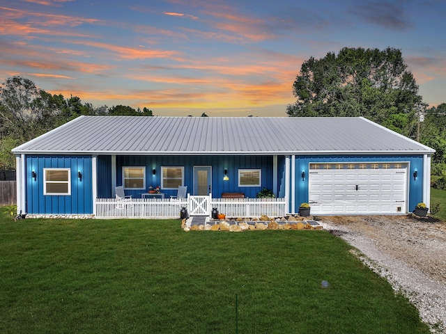 ranch-style home featuring covered porch, a yard, and a garage