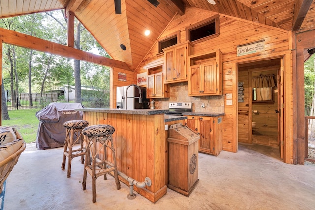 kitchen featuring sink, wood walls, electric range, and a kitchen bar