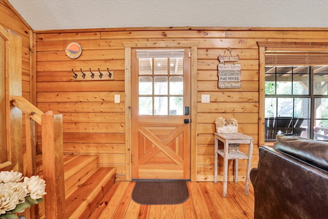 doorway to outside featuring wood walls, a textured ceiling, and hardwood / wood-style floors