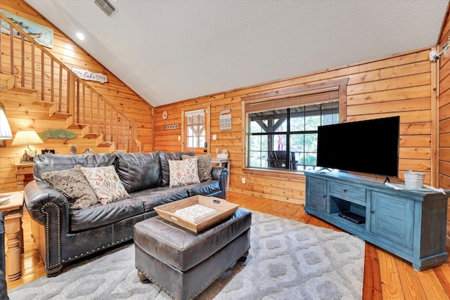 living room featuring wooden walls, vaulted ceiling, and wood-type flooring