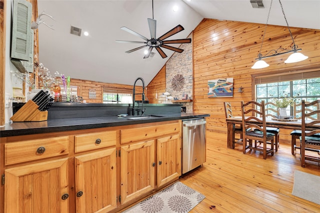 kitchen featuring sink, light wood-type flooring, dishwasher, ceiling fan, and wooden walls