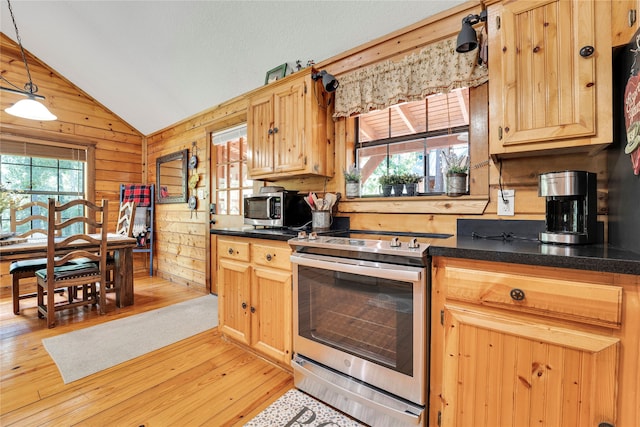 kitchen featuring stainless steel range with electric stovetop, hanging light fixtures, light hardwood / wood-style floors, lofted ceiling, and wooden walls