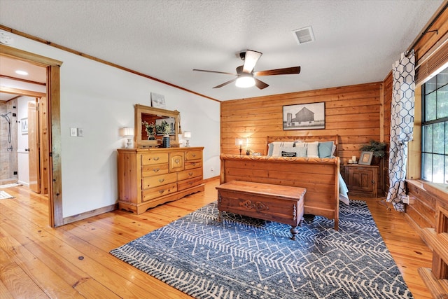 bedroom featuring wood-type flooring, crown molding, ceiling fan, a textured ceiling, and wood walls