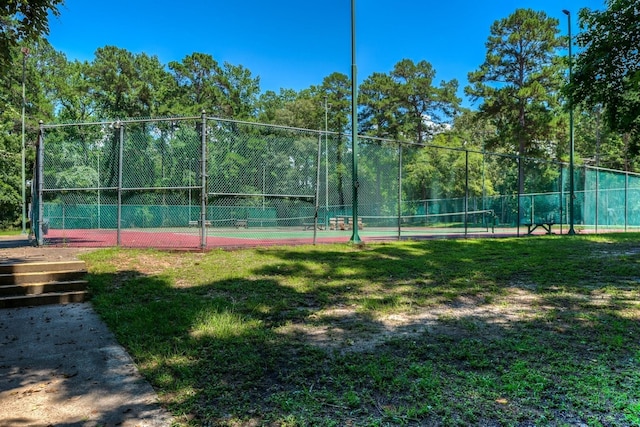 view of tennis court featuring a yard