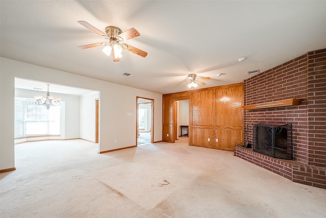 unfurnished living room with light carpet, a fireplace, wooden walls, and ceiling fan with notable chandelier