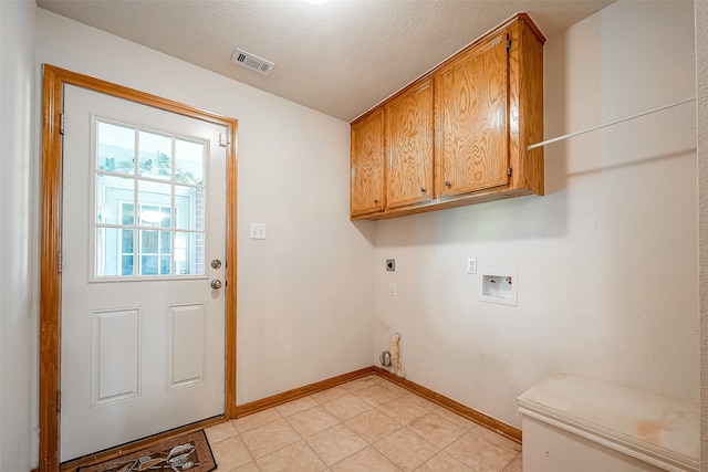 washroom with electric dryer hookup, washer hookup, light tile patterned floors, a textured ceiling, and cabinets