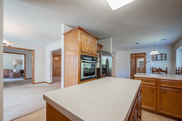 kitchen featuring a textured ceiling, a center island, hanging light fixtures, stainless steel appliances, and light tile patterned floors