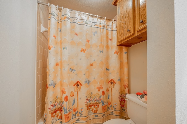 bathroom with toilet, a textured ceiling, and a shower with shower curtain