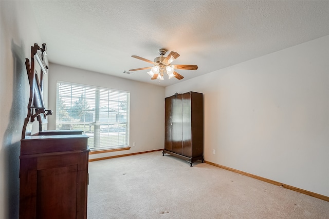 unfurnished bedroom featuring a textured ceiling, light colored carpet, and ceiling fan