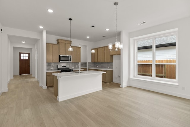 kitchen with tasteful backsplash, stainless steel appliances, sink, pendant lighting, and an island with sink