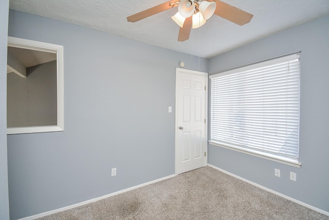 spare room featuring light carpet, ceiling fan, and a textured ceiling