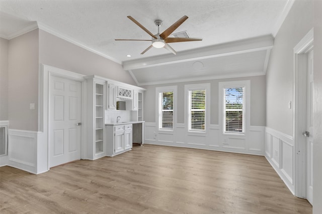 unfurnished living room with a textured ceiling, lofted ceiling with beams, light hardwood / wood-style flooring, and ornamental molding