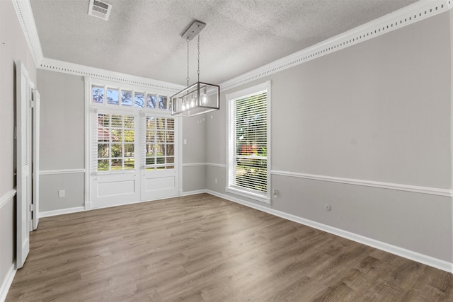 unfurnished dining area with ornamental molding, a textured ceiling, and hardwood / wood-style flooring