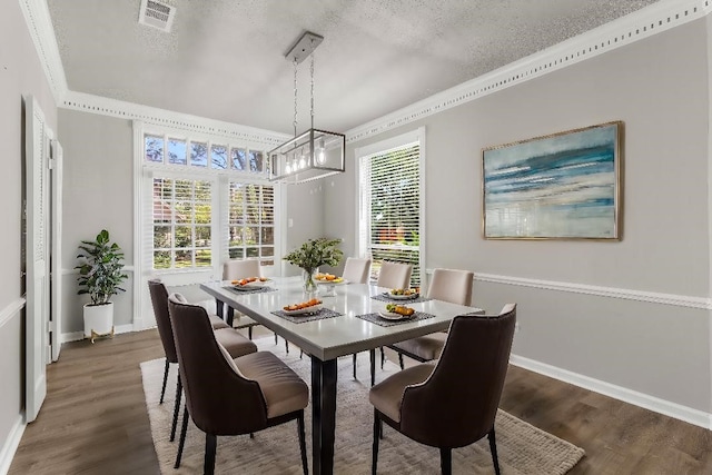 dining space featuring dark hardwood / wood-style floors, a textured ceiling, and ornamental molding