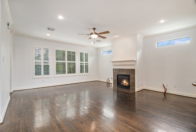 unfurnished living room with a tiled fireplace, ceiling fan, dark hardwood / wood-style floors, and crown molding