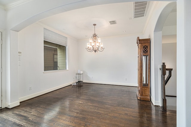 empty room featuring dark hardwood / wood-style flooring, a chandelier, and crown molding