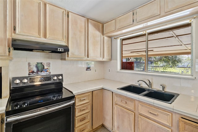 kitchen with light brown cabinets, electric range, backsplash, tile counters, and sink