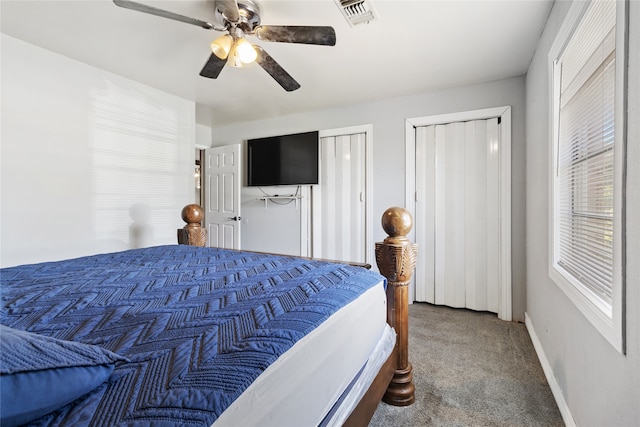 bedroom with ceiling fan, carpet floors, and two closets