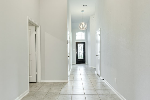 foyer with an inviting chandelier, a high ceiling, and light tile patterned floors