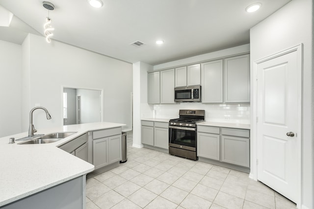 kitchen with tasteful backsplash, light tile patterned floors, appliances with stainless steel finishes, gray cabinets, and sink