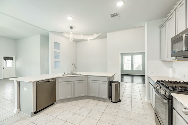 kitchen with light tile patterned flooring, stainless steel appliances, sink, gray cabinets, and decorative light fixtures