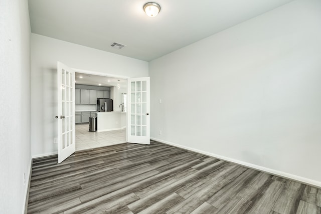 empty room with french doors and light wood-type flooring