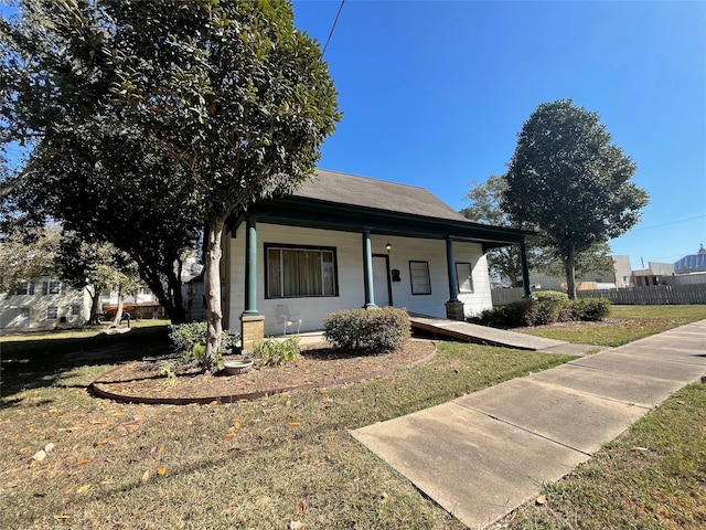 bungalow-style house featuring covered porch, roof with shingles, fence, and a front yard